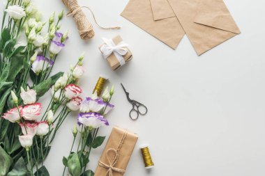 Üstten Görünüm sarılı eustoma, hediyeler, makaralar iplik, Zarflar ve gri arka plan üzerinde makas