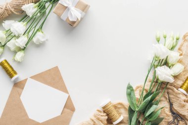 eustoma, sarılmış hediye, zarf boş oyun kağıdı, makas ve gri arka plan üzerine kumaş ile Üstten Görünüm 
