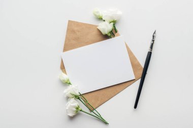 gri arka plan üzerinde eustoma, zarf boş oyun kağıdı ve tükenmez kalem ile Üstten Görünüm