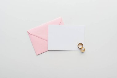 gri arka plan üzerinde pembe zarf ve altın alyans ile boş kartı Üstten Görünüm