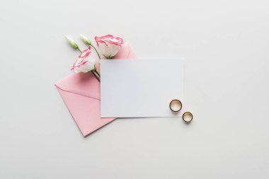 pembe zarf, çiçek ve altın alyans boş oyun kağıdı üstten görünüm gri arka plan üzerinde