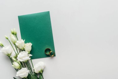gri arka plan üzerinde boş yeşil zarf, eustoma ve altın alyans Üstten Görünüm