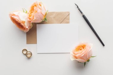 gri arka plan üzerinde kahverengi craft kağıt zarf, tükenmez kalem, çiçek ve alyans boş kartı Üstten Görünüm