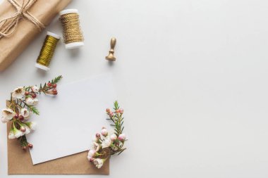 gri arka plan üzerinde kahverengi zarf, çiçek, damga, sarılmış hediye ve iş parçacığının biriktiricileri boş boş Üstten Görünüm