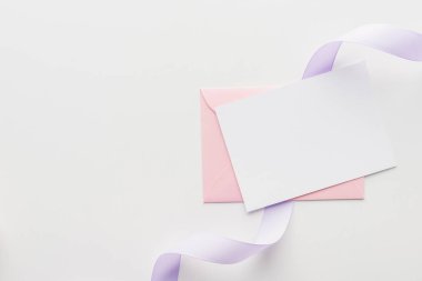 pembe zarf ve mor ipek kurdele ile boş boş üstten görünüm gri arka plan üzerinde