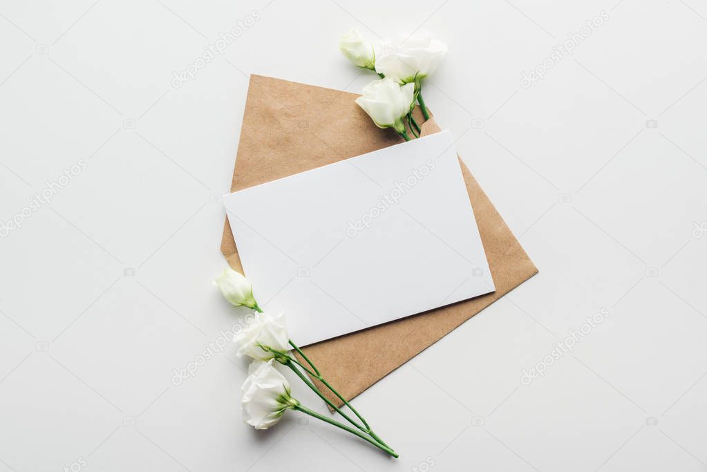 top view of eustoma and envelope with empty card on grey background 
