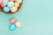 top view of traditional pastel easter eggs in wicker basket isolated on blue with copy space
