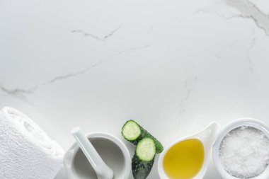 Beyaz yüzeyinde yağ ve tuz, salatalık yarısı, pounder ve havlu ile kase Üstten Görünüm