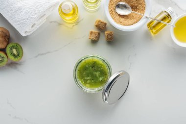 cam kabın kivi püresi ve kozmetik beyaz yüzey üzerinde yapmak için çeşitli bileşenleri ile Üstten Görünüm