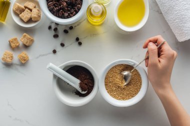 kırpılan görünümünü kaşığı esmer şeker ile pounder çekilmiş kahve ile ve kozmetik beyaz yüzey üzerinde yapmak için çeşitli malzemeler tutan kadın