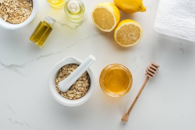 top view of pounder with oat flakes, bowl with honey, lemons and various components on white surface clipart