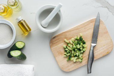 Ahşap Kesim Masası kesilmiş salatalık küpleri, pounder ve kozmetik beyaz yüzey üzerinde yapmak için farklı malzemeler ile top