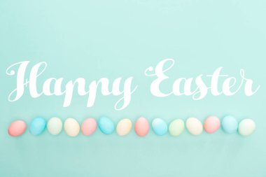 Üstten Görünüm satırda mavi izole mutlu Paskalya yazı ile pastel boyalı yumurta