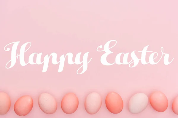 Happy Easter lettering with traditional painted eggs in row isolated on pink