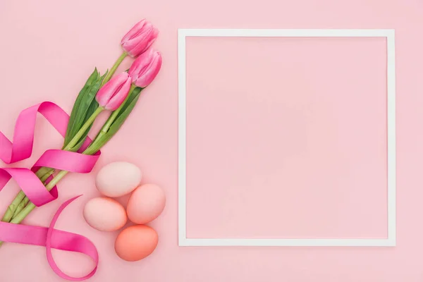 粉红色郁金香和复活节彩蛋的顶部视图与框架隔离在粉红色 — 图库照片