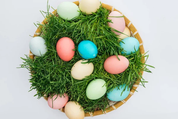 Bovenaanzicht Van Kleurrijke Paaseieren Rieten Plaat Met Gras Geïsoleerd Wit — Stockfoto