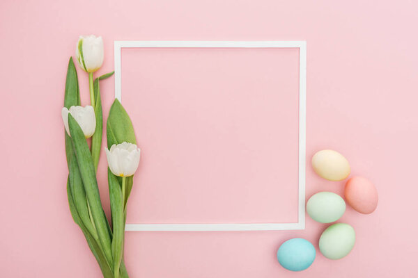 top view of frame with tulips and pastel easter eggs isolated on pink