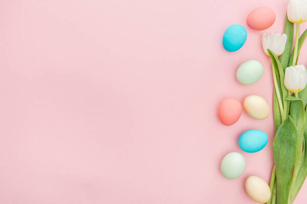 top view of tulip flowers and easter eggs isolated on pink with copy space