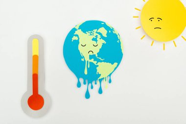 Güneş ve yüzleri üzgün ifade ile eritme toprak ve yüksek sıcaklık göstergesi ile termometre gri arka plan, küresel ısınma konsepti ölçekte kağıt kesme 