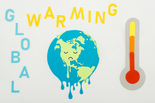 плавильный глобус с грустным выражением лица, надписью "глобальное потепление" и термометром с высокой температурой на сером фоне

