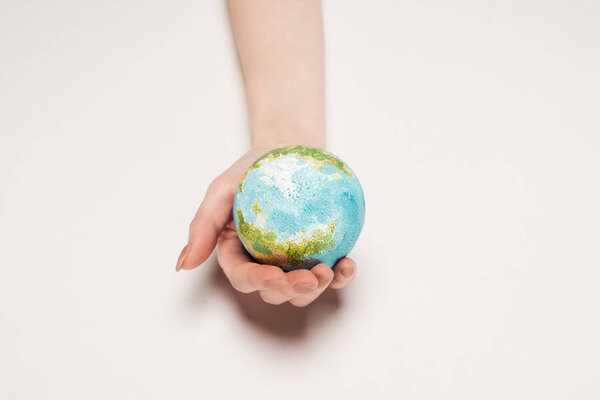 частичный взгляд на женскую руку с моделью Земли на белом фоне, концепция глобального потепления
