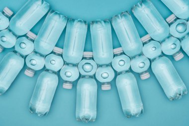 şeffaf plastik su şişeleri üzerinde turkuaz izole satırlar halinde yerleştirilmiş, üstten görünüm