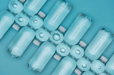 plastik su şişeleri üzerinde turkuaz izole satırlar halinde yerleştirilmiş, üstten görünüm