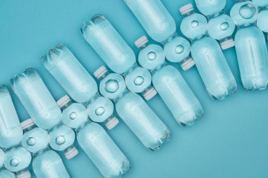 plastik su şişeleri üzerinde turkuaz izole satırlar halinde yerleştirilmiş, üstten görünüm