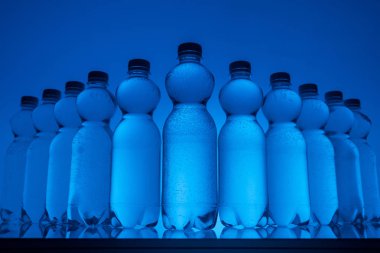görüntü satırında neon mavi zemin üzerine su ile plastik şişe tonda