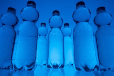 plastik su şişeleri satırlar halinde neon mavi arka plan görüntüsünü tonda