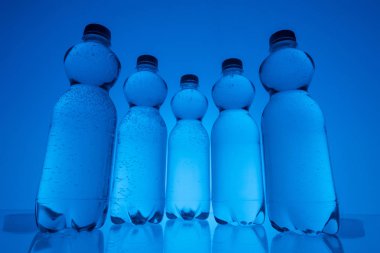 plastik su şişeleri satırındaki neon mavi arka plan görüntüsünü tonda
