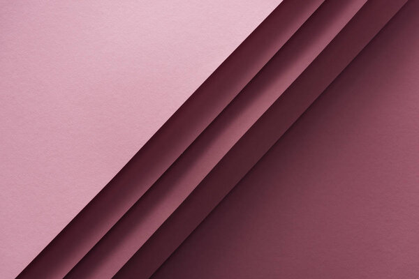 top view of blank and pink sheets of paper on burgundy background 