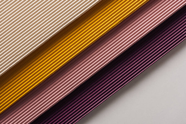 top view of white, yellow, pink, purple papers on white background with copy space 