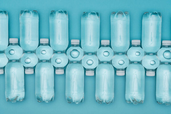 top view of arranged plastic water bottles isolated on turquoise
