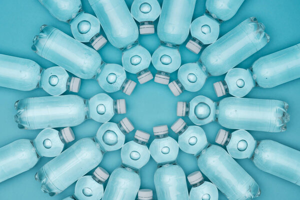 top view of transparent plastic water bottles isolated on turquoise