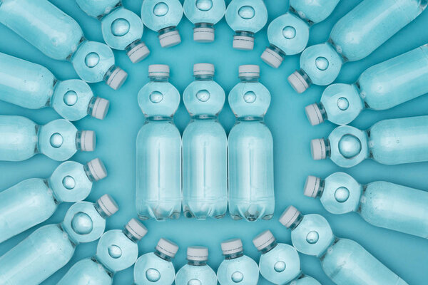 top view of transparent plastic water bottles isolated on turquoise