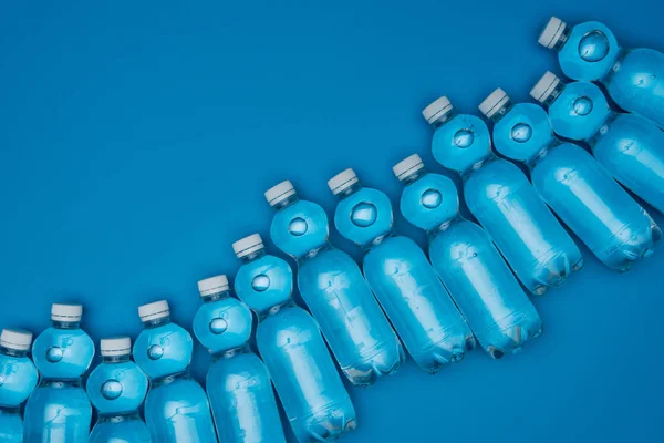 コピー スペースと青に分離された行にペットボトルの水の上から見る — ストック写真