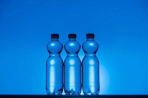 Imagen Tonificada Botellas Agua Plástico Transparente Sobre Fondo Azul Neón — Foto de Stock