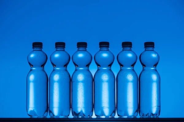 Tonad Bild Plast Vattenflaskor Neon Blå Bakgrund Med Motljus — Stockfoto