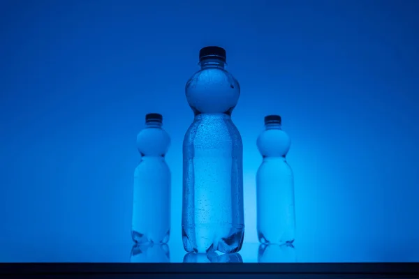 Imagen Tonificada Botellas Agua Plástico Sobre Fondo Azul Neón Con — Foto de Stock