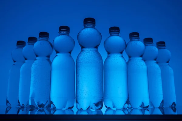 Tonas Bild Transparent Plast Flaskor Med Vatten Neon Blå Bakgrund — Stockfoto
