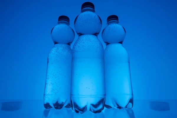Imagen Tonificada Botellas Agua Plástico Fila Sobre Fondo Azul Neón —  Fotos de Stock