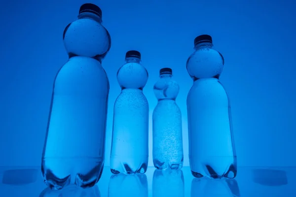 Vista Basso Angolo Bottiglie Acqua Plastica Trasparente Sfondo Blu Neon — Foto Stock