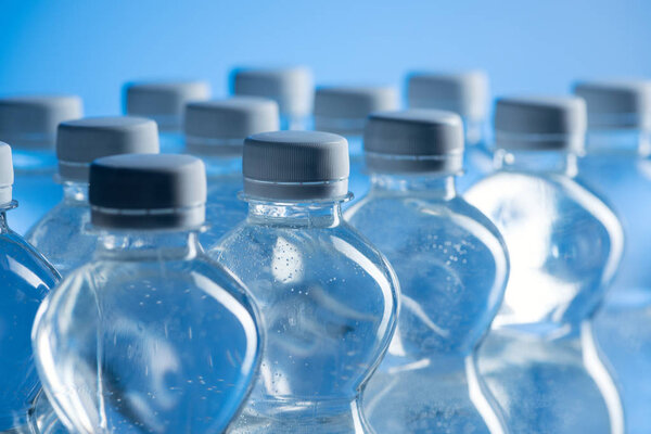 селективный фокус пластиковых бутылок с водой, изолированных на синий
