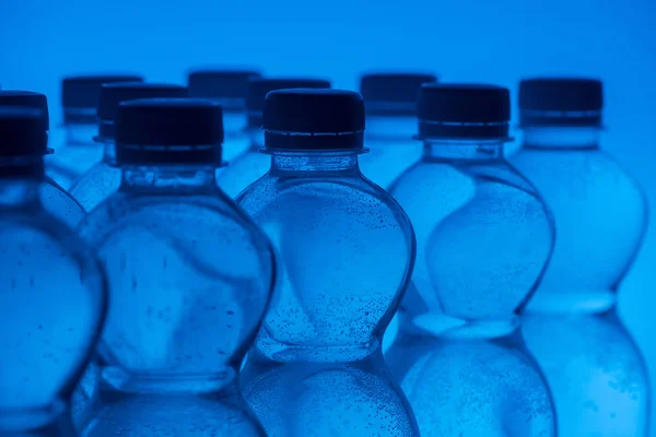 Közelkép Műanyag Palackokkal Sorokban Neon Kék Háttér — Stock Fotó