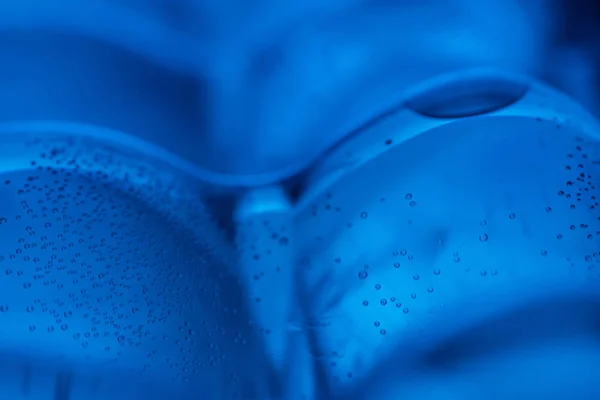 파란색 배경에 거품과 플라스틱 물병의 클로즈업 — 스톡 사진
