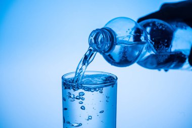 Kısmi su cam plastik şişe mavi zemin üzerine dökülen adam görünümünü