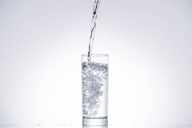 background of water pouring in glass on white with backlit and copy space clipart