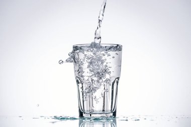 water pouring in glass on white background with backlit, splashes and copy space clipart