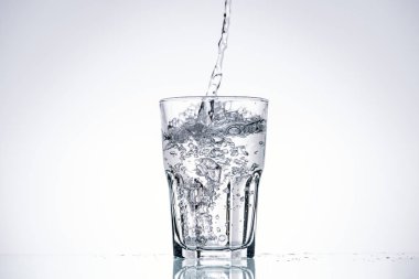 water pouring in drinking glass on white background with backlit and copy space clipart